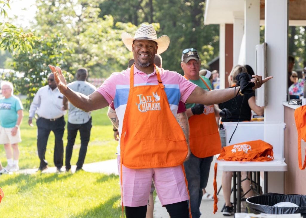 A man wearing a jail chaplains apron and smiling.