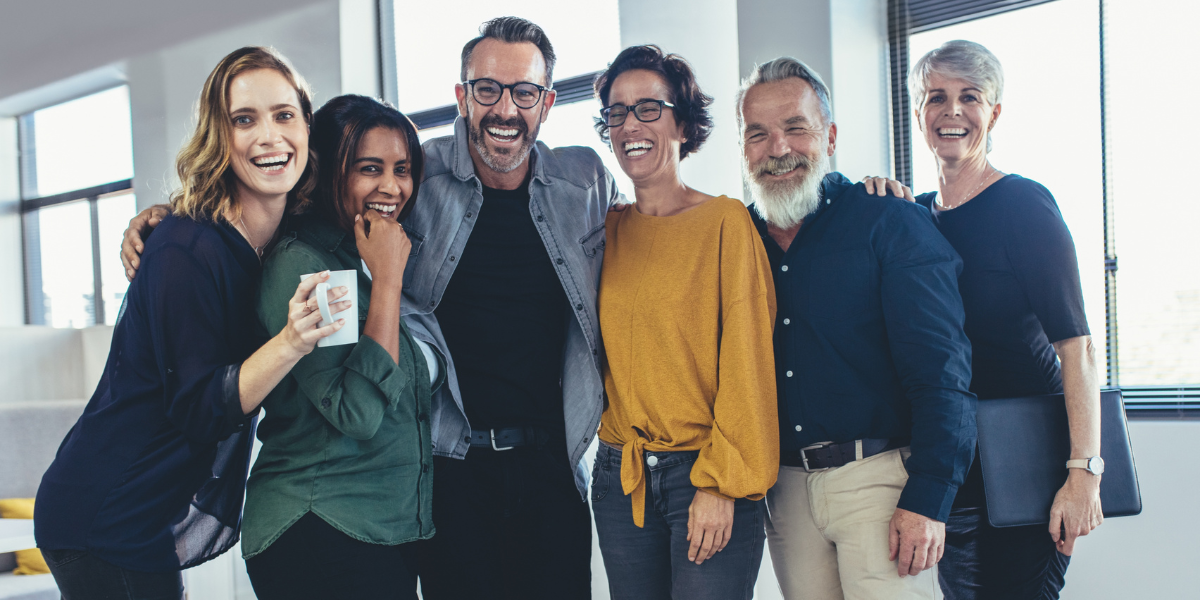 A group of business professionals together posing for a picture and laughing.